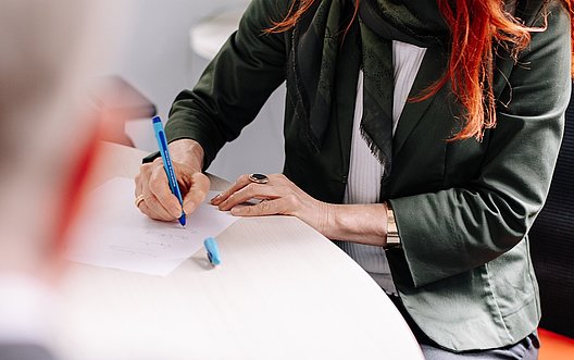 Person macht Notizen auf einem Papierbogen