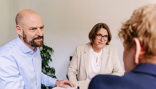 Drei Personen im Gespräch in einem Büro