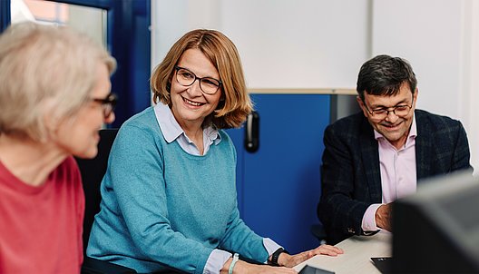Drei Personen im Gespräch an einem Tisch